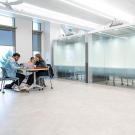 A view of the main Writing Center floor with two students working at a table to the far left.