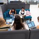 A photo taken from above looking down on a group of five students working in a booth in the Writing Center.