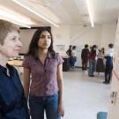 Two women study a research poster in a bright lab, focused expressions